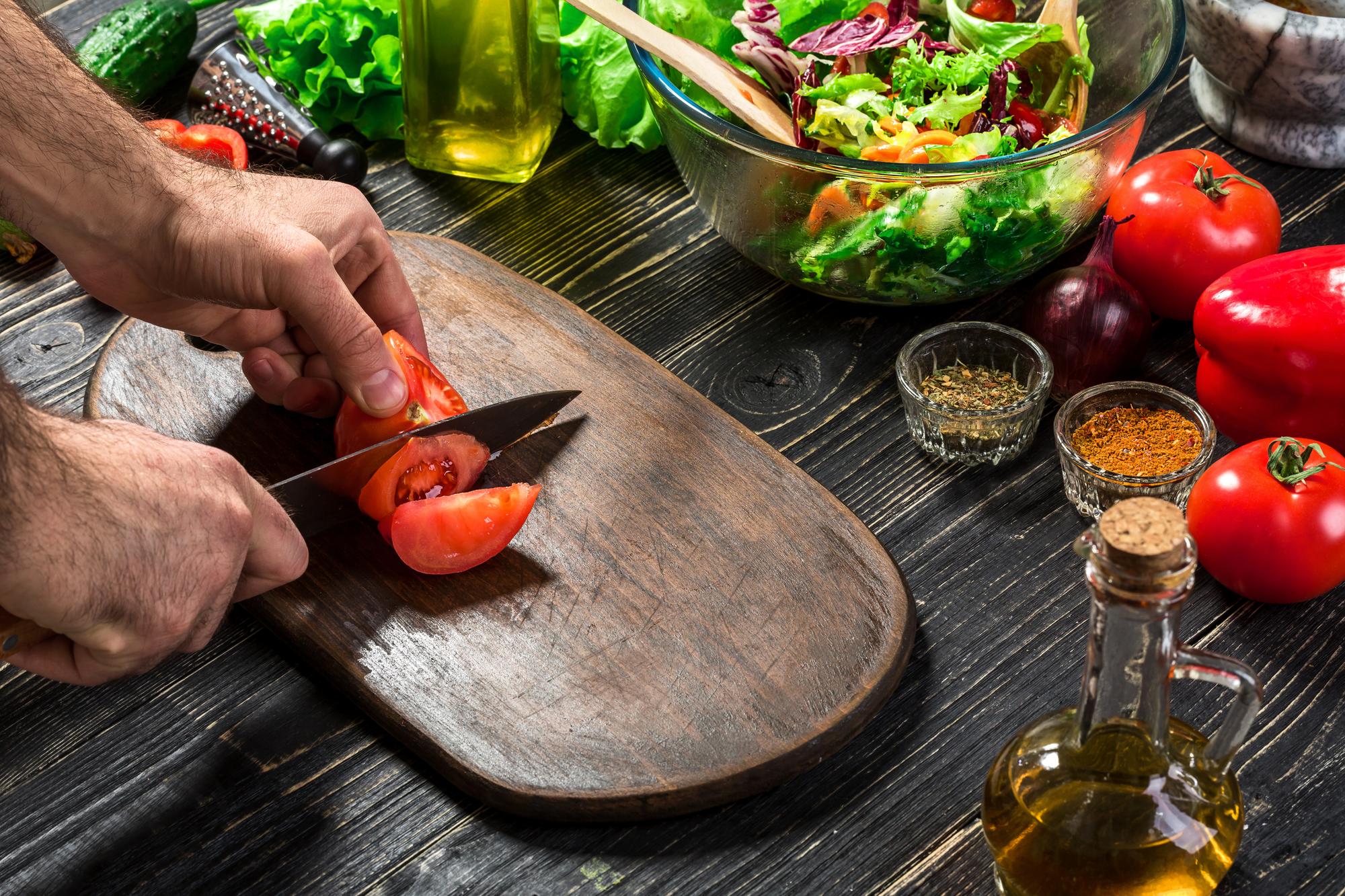 Instructor slicing seasonal vegetables on wooden board